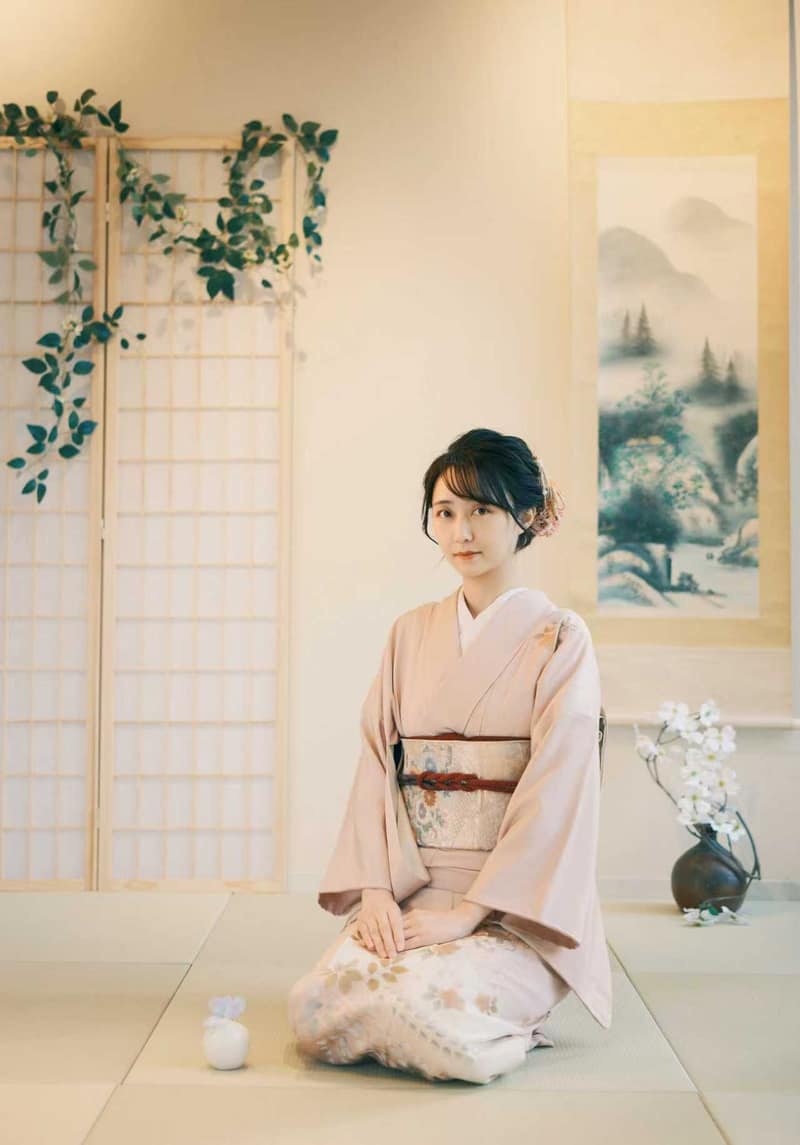 浅粉色和服正坐于榻榻米上,背景是障子门、挂轴与插着花的花器