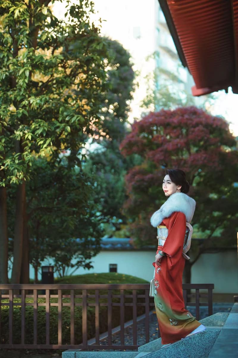 Deep red kimono with a soft gradient hem and a white fur stole, photographed beside a garden railing
