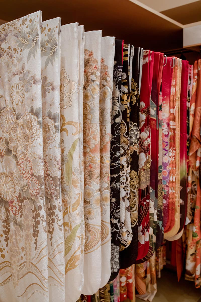 Rental kimono hanging side by side on a rail, from pale ivory through to deep red