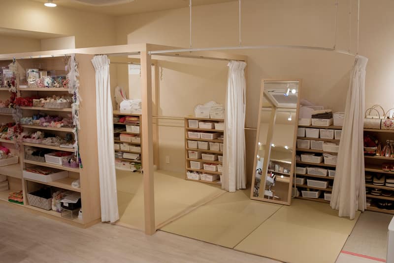Curtained dressing booths on tatami flooring, with a full-length mirror and accessory shelves