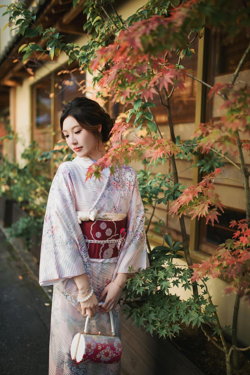 Komon kimono in a pale shade with small repeating flowers, worn with a red obi